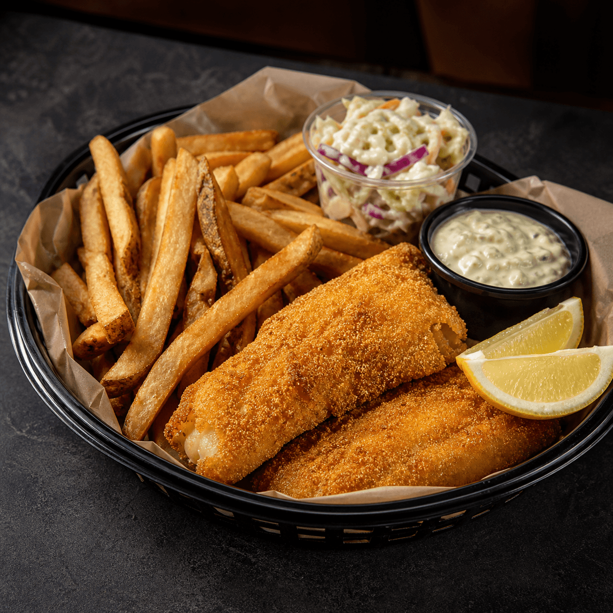 Cornmeal-crusted fried fish basket with Kennebec fries, coleslaw, tartar sauce, and lemon plated final result